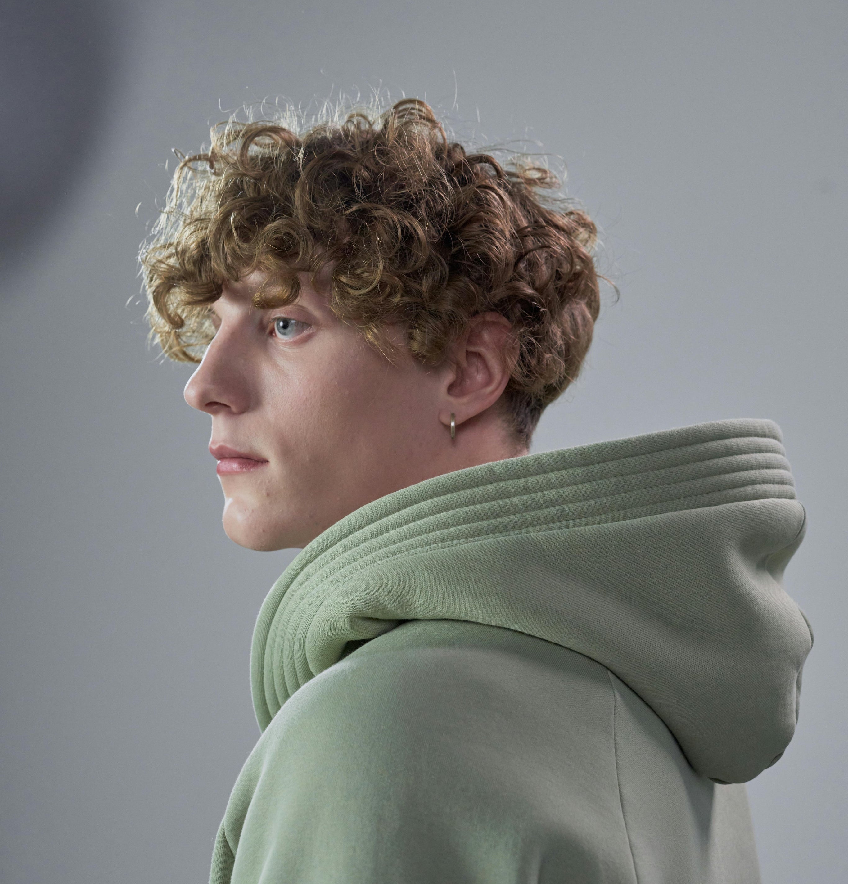 Person wearing a light green hoodie against a gray background